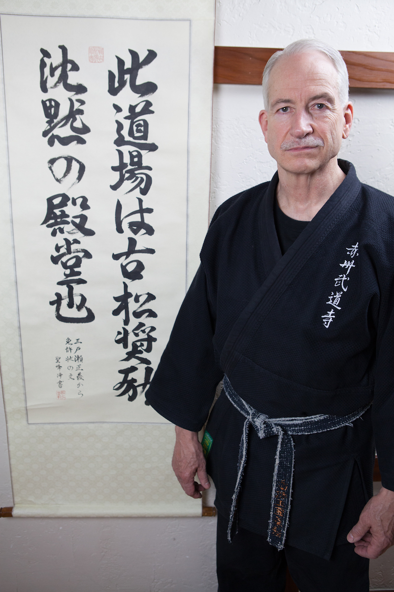 Roland S. Roemer, Founder and Academy Director of CAMA, standing before a Japanese calligraphy scroll